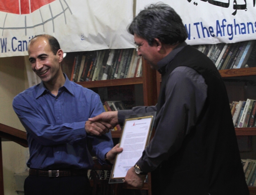 ACCC Director Ehsanullah Ehsan presents a letter of recognition to Mr Karzai